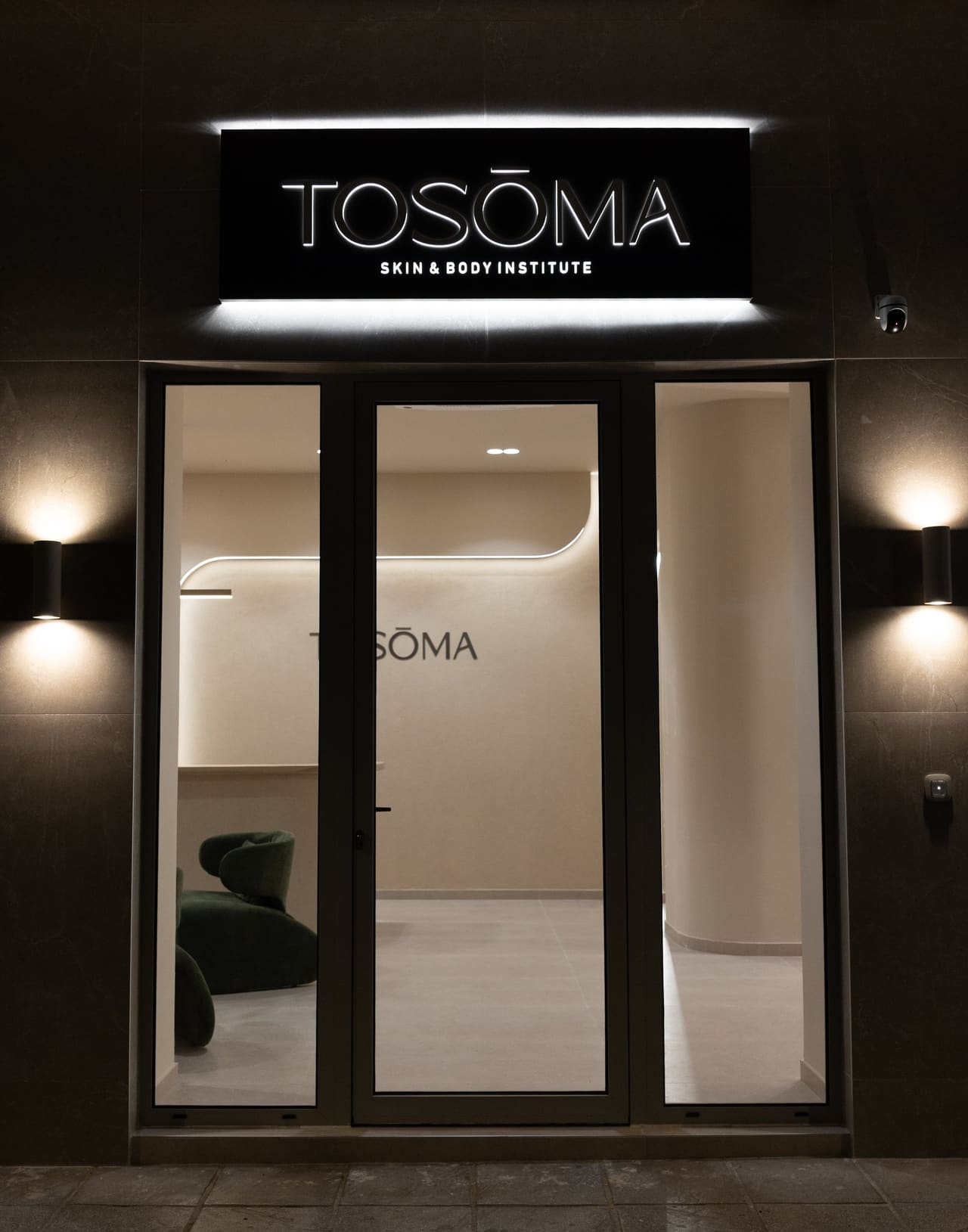 Η πρόσοψη του TOSŌMA τη νύχτα με φωτισμένη επιγραφή